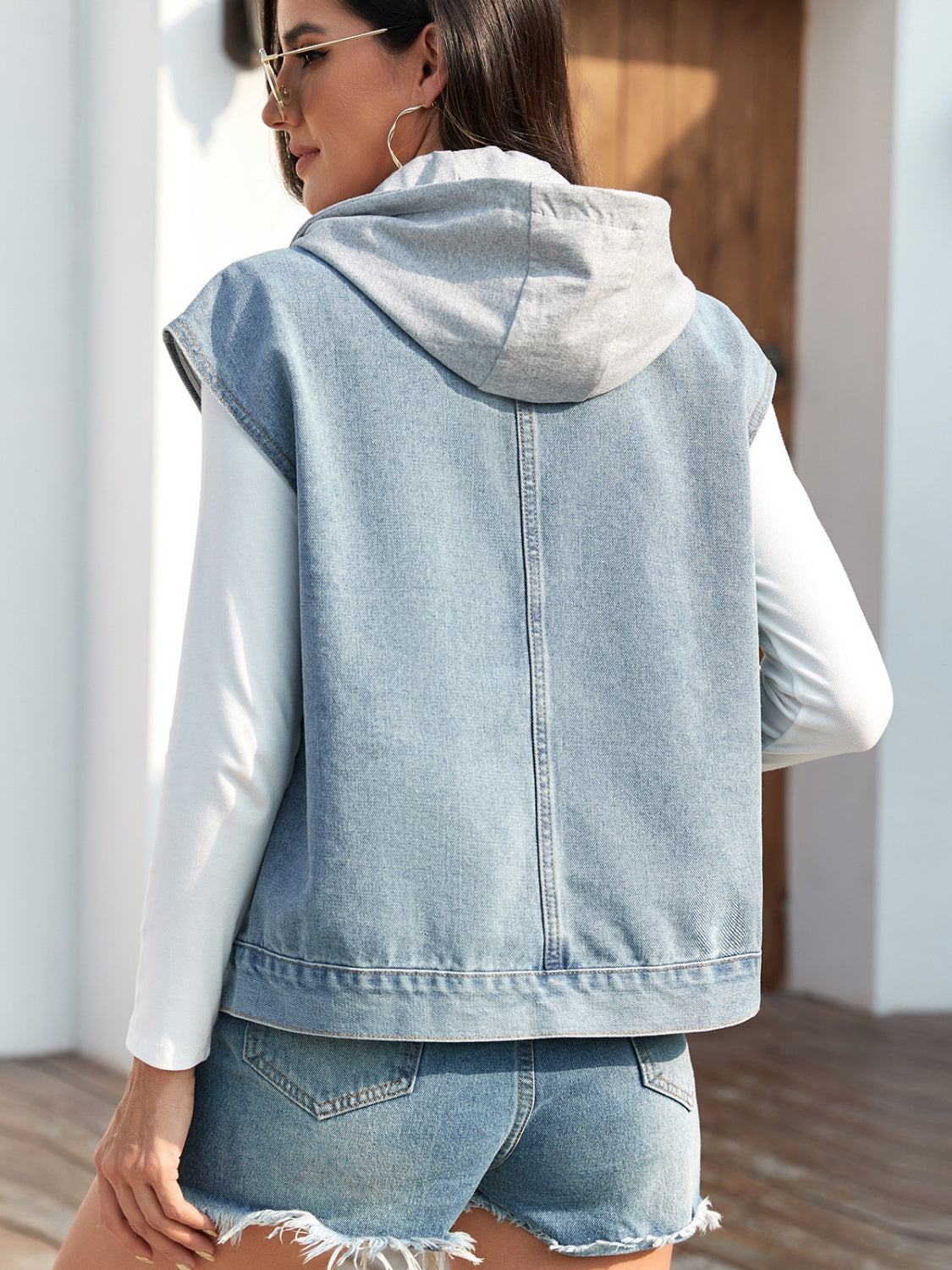 Sleeveless denim jacket with drawstring hood and button-up front.