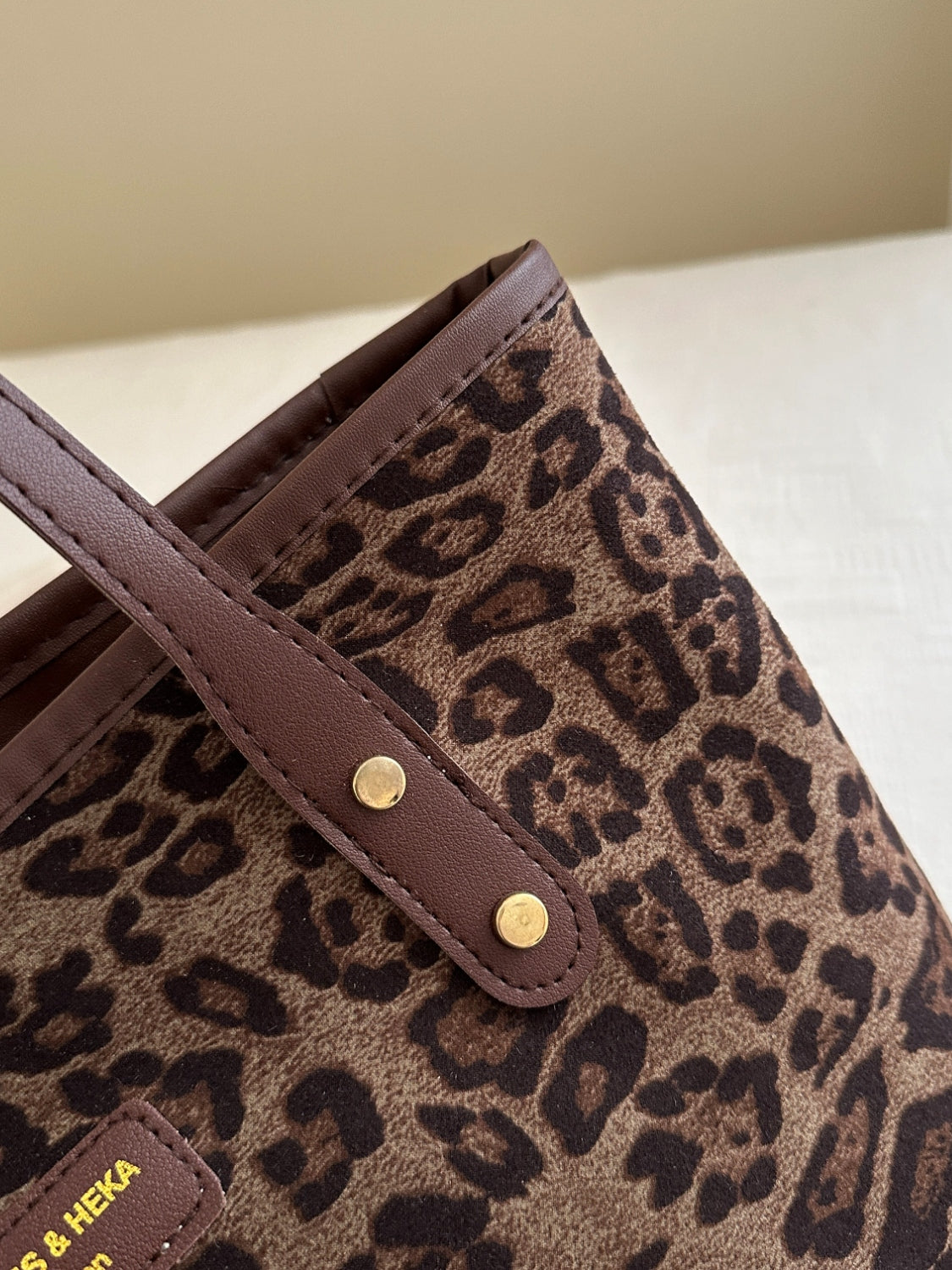 Leopard polyester tote bag with brown leather straps.