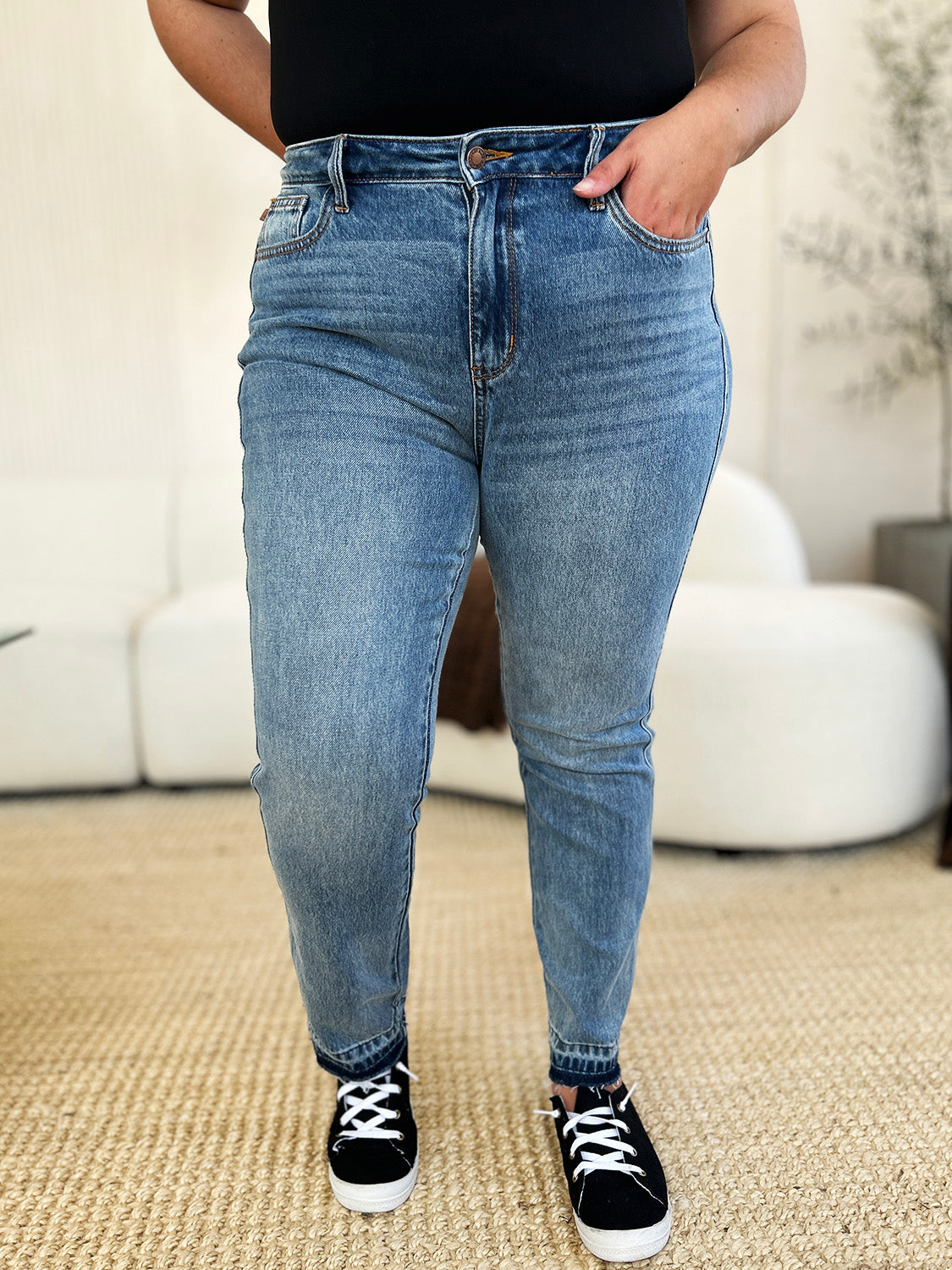 Judy Blue full size mid rise jeans with magic release hem, worn with black sneakers, front view.