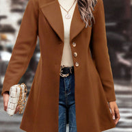 Collared neck button up long sleeve coat in brown with gold buttons, worn over a cream turtleneck sweater and blue jeans.