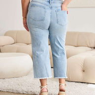 RFM Full Size Tummy Control High Waist Raw Hem Distressed Jeans on a model in a living room setting.