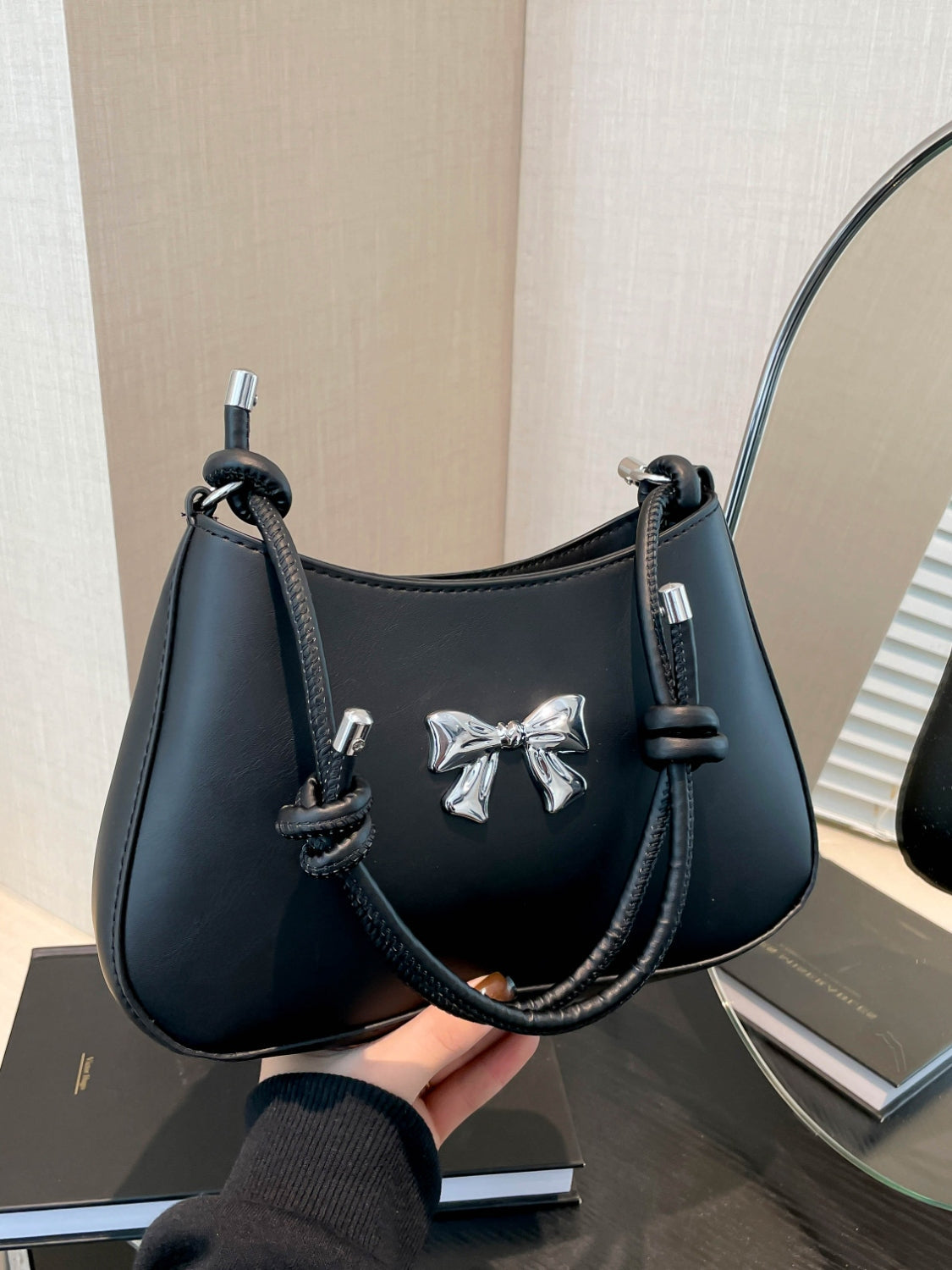 Small black PU leather handbag with knotted strap and bow detail.