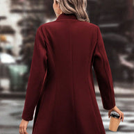 Woman wearing burgundy collared neck button-up long sleeve coat on city street.