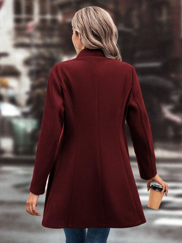 Woman wearing burgundy collared neck button-up long sleeve coat on city street.