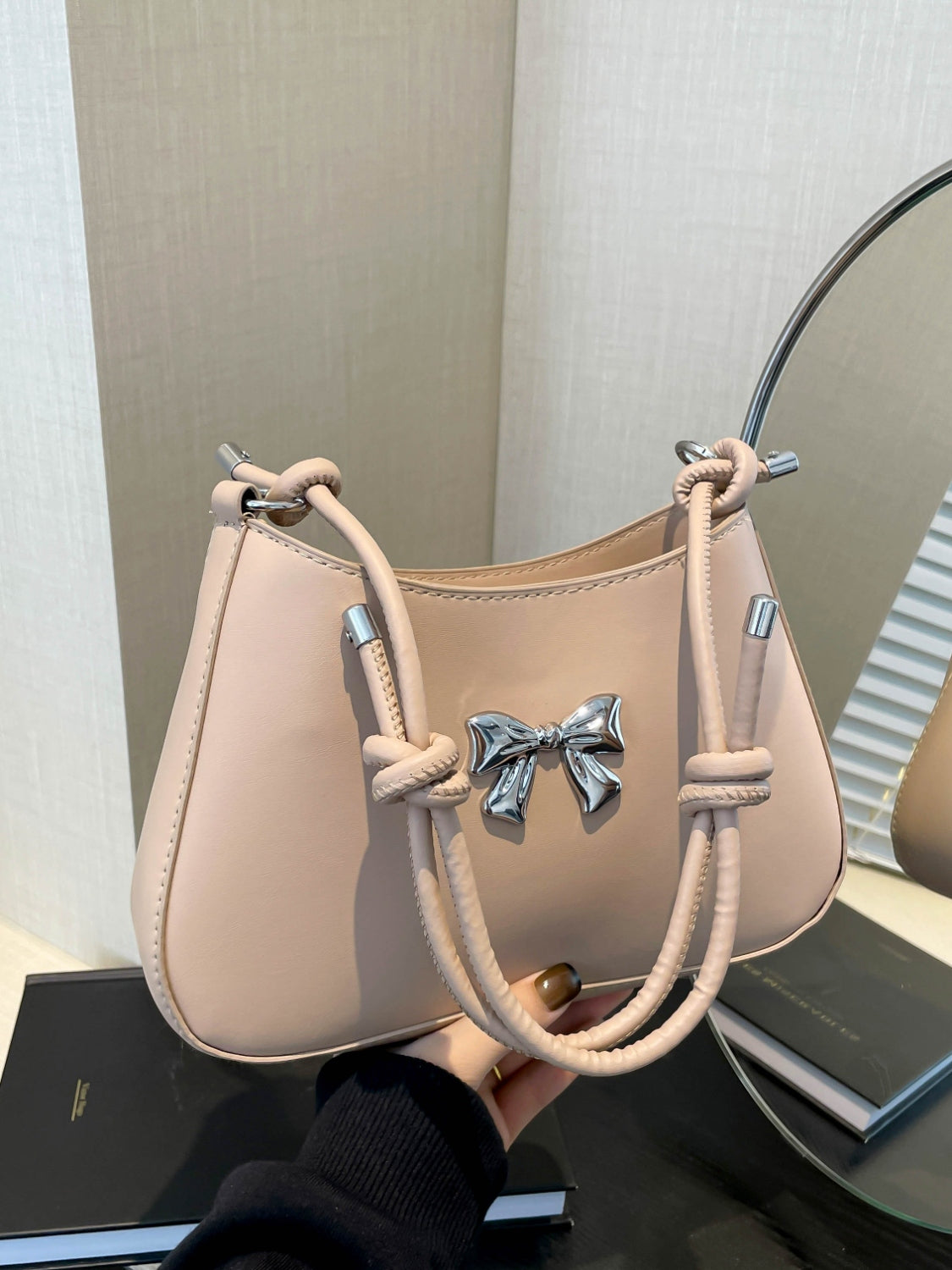 Small PU leather handbag with knotted strap and bow detail.