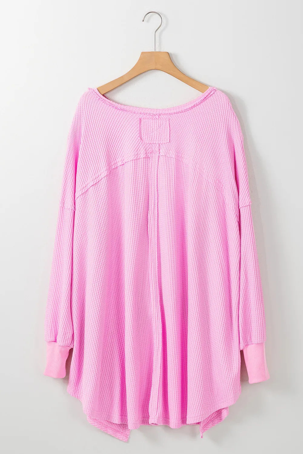 Pink waffle-knit V-neck long sleeve blouse on hanger.